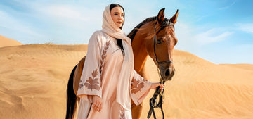 selhaya abayas - abaya wearing a woman carrying a horse in desert